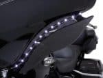 Sleek black Harley Davidson touring motorcycle with LED accent lighting in dark setting.