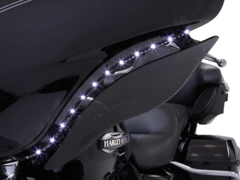 Sleek black Harley Davidson touring motorcycle with LED accent lighting in dark setting.