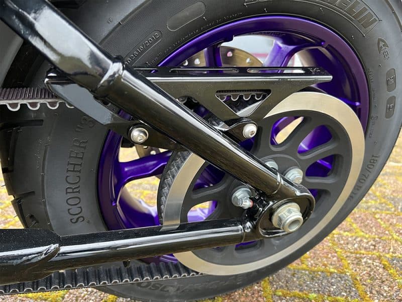 High-performance motorcycle rear wheel with purple accents and advanced suspension system.