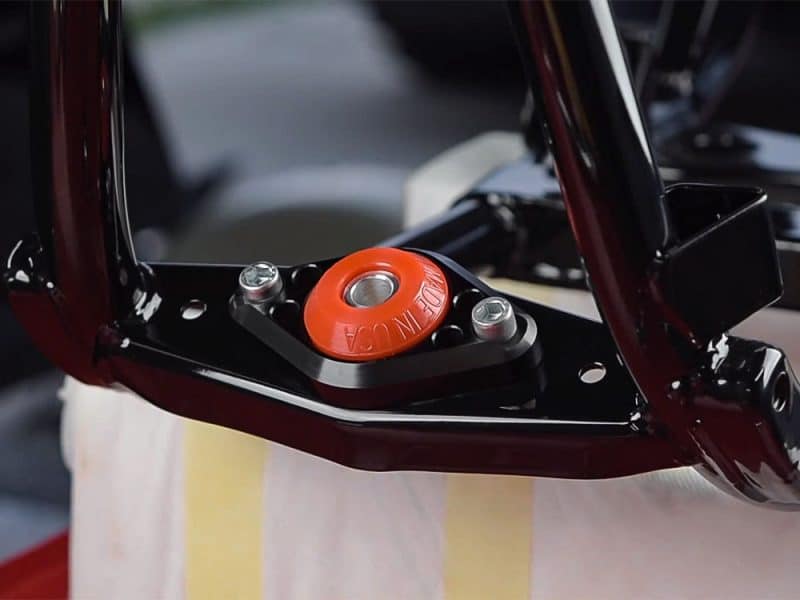 Red motorcycle steering damper with Revelry logo for enhanced handling and stability.