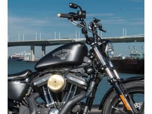 Harley Davidson motorcycle near port, black matte finish, chrome details, urban coastal scene.