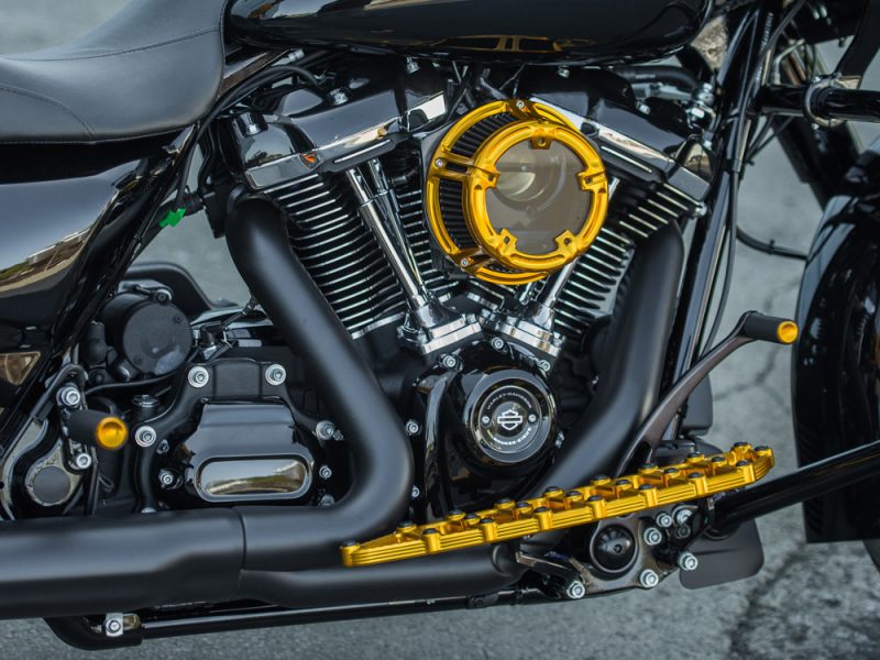 Vivid black motorcycle engine with gold accents and custom detailing, showcasing high-performance parts and alloy components.