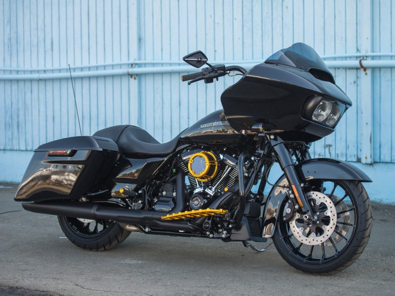 Vivid black touring motorcycle with custom yellow accents and hard saddle bags for long-distance riding.