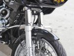 Riveting motorcycle front suspension and front wheel close-up, showcasing advanced design and materials.