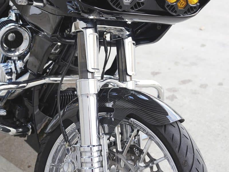 Riveting motorcycle front suspension and front wheel close-up, showcasing advanced design and materials.