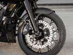 High-performance motorcycle front wheel with disc brake, carbon fibre fender, and rugged tyre.