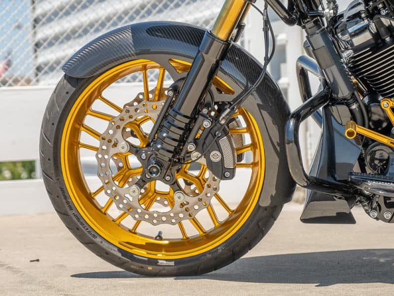 Golden alloy motorcycle wheel with disc brake and black front suspension, Levi's Revelry Motorcycles AU.
