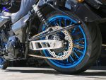 High-performance motorcycle rear wheel with blue rim and custom chain drive.