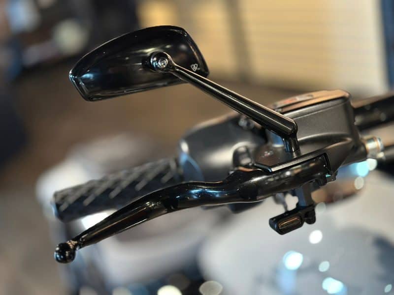 Black motorcycle mirror and handlebars at Revelry Motorcycles, showcasing premium bike accessories.