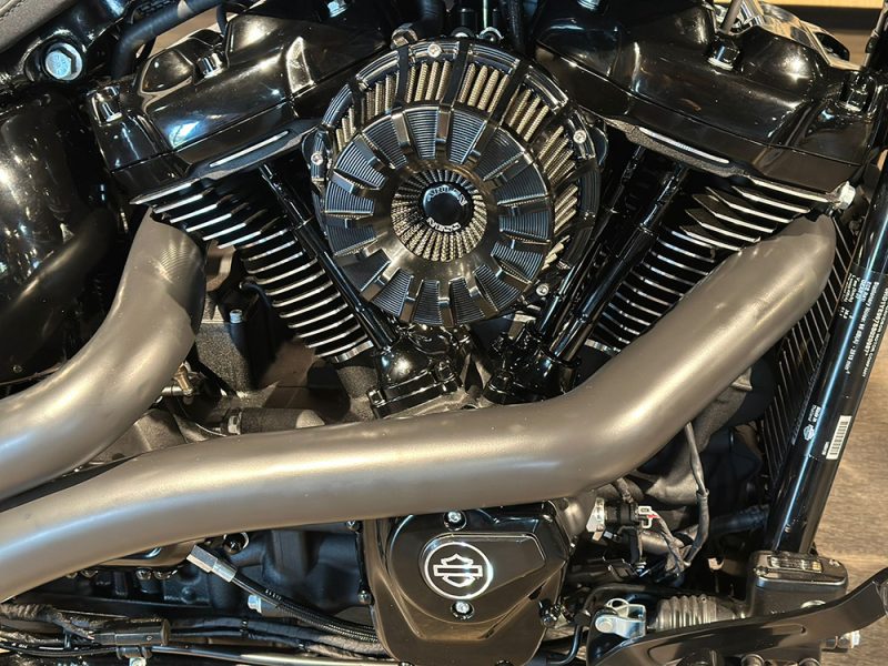 Vibrant black motorcycle engine with chrome accents and matte exhaust pipes.