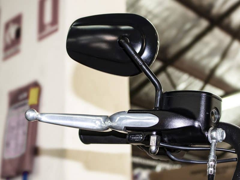 Black motorcycle mirror and handlebar close-up at Revelry Motorcycles, showcasing premium motorcycle accessories.
