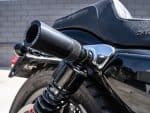 Black motorcycle exhaust pipe and suspension on a sleek black cruiser bike.