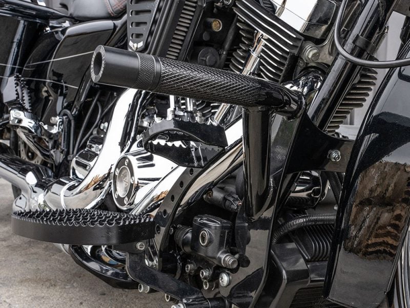 Black motorcycle handlebar and engine close-up at Revelry Motorcycles, showcasing custom parts and high-quality craftsmanship.