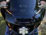 Shiny black motorcycle front view with LED headlights and turn signals, outdoor setting.