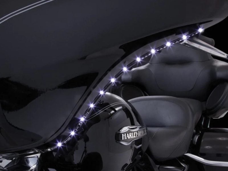 Shiny black Harley-Davidson motorcycle with LED accent lighting and leather seats for cruising.