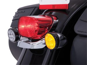 Bright red motorcycle tail light with integrated turn signals on black bike, ideal for road safety.