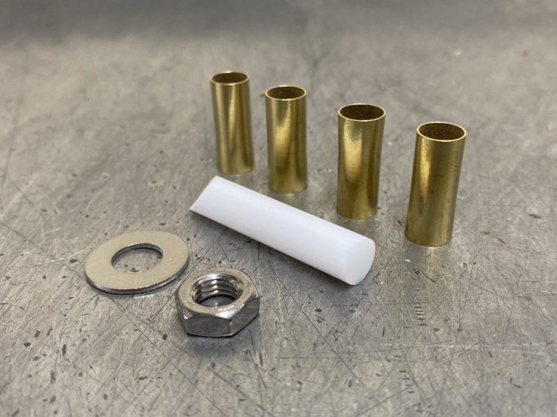 Brass and metal spacers with nut and washer for motorcycle maintenance and upgrades.