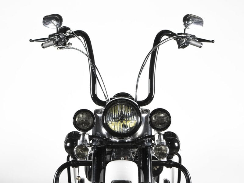 Motorcycle handlebars with headlight and mirrors, classic cruiser style, black and chrome details.