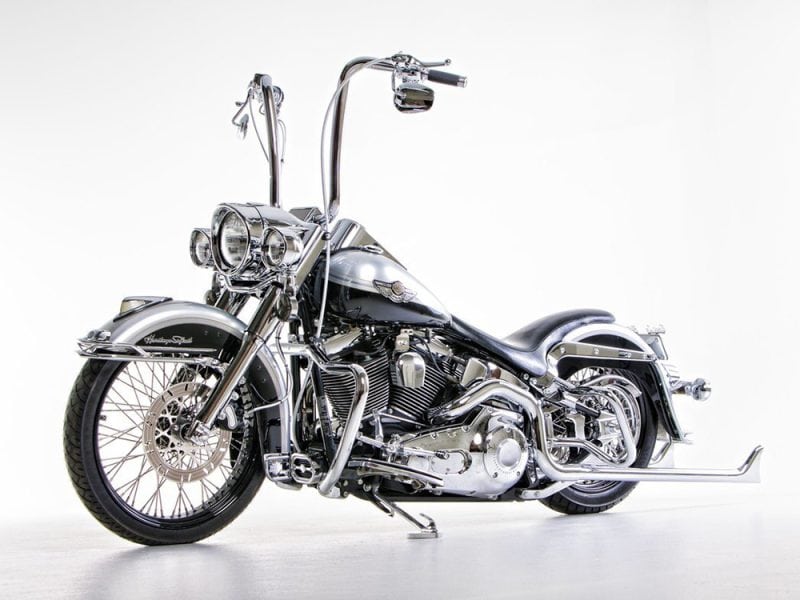 Shiny black and chrome Harley-Davidson motorcycle with custom high handlebars.