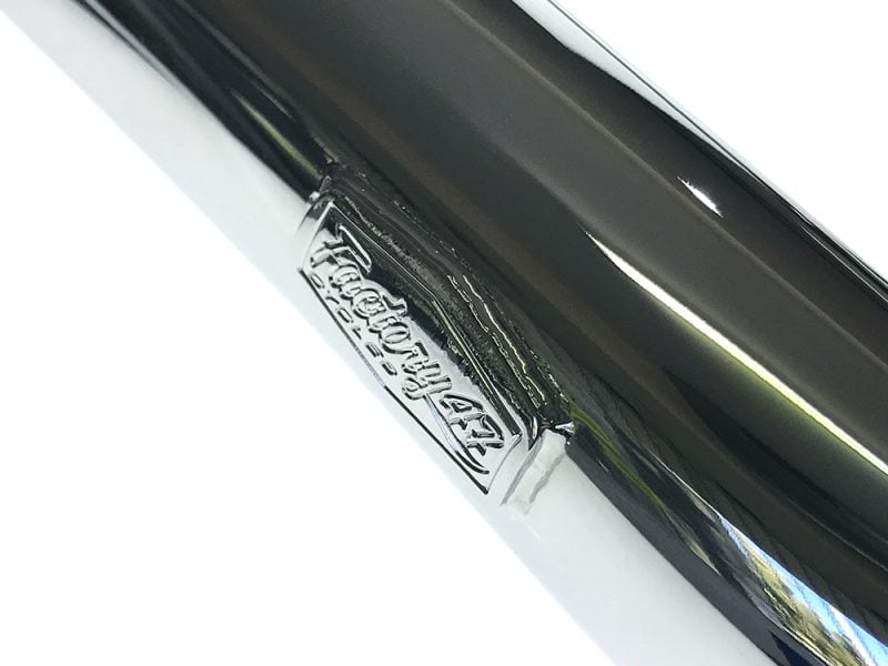 Shiny motorcycle exhaust with Revelry Motorcycles logo in chrome finish.