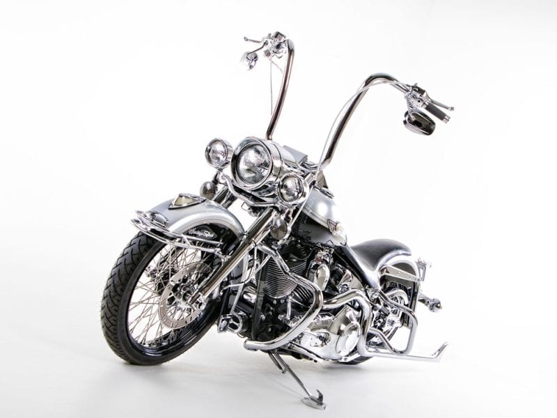 Shiny custom chrome motorcycle with high handlebars and vintage style, perfect for motorcycle enthusiasts.
