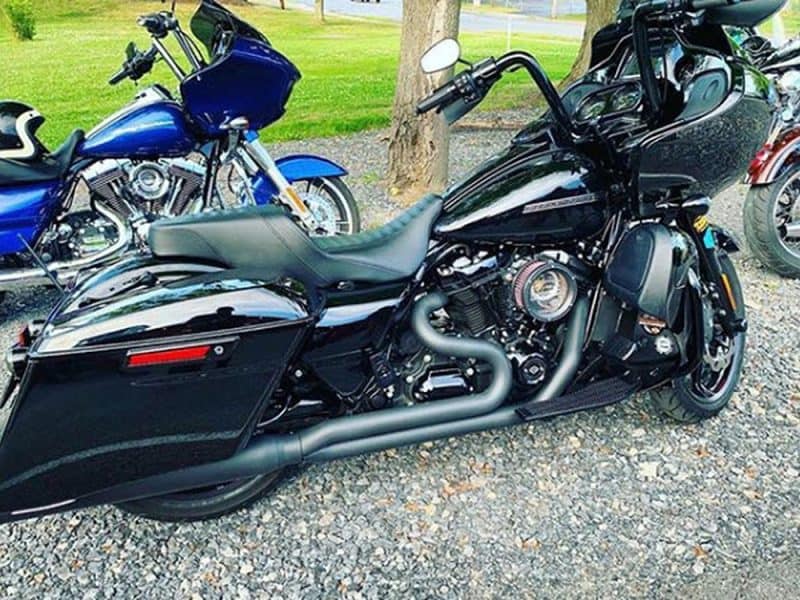 Luxury black motorcycle with custom exhaust pipes and sleek design in an outdoor setting.