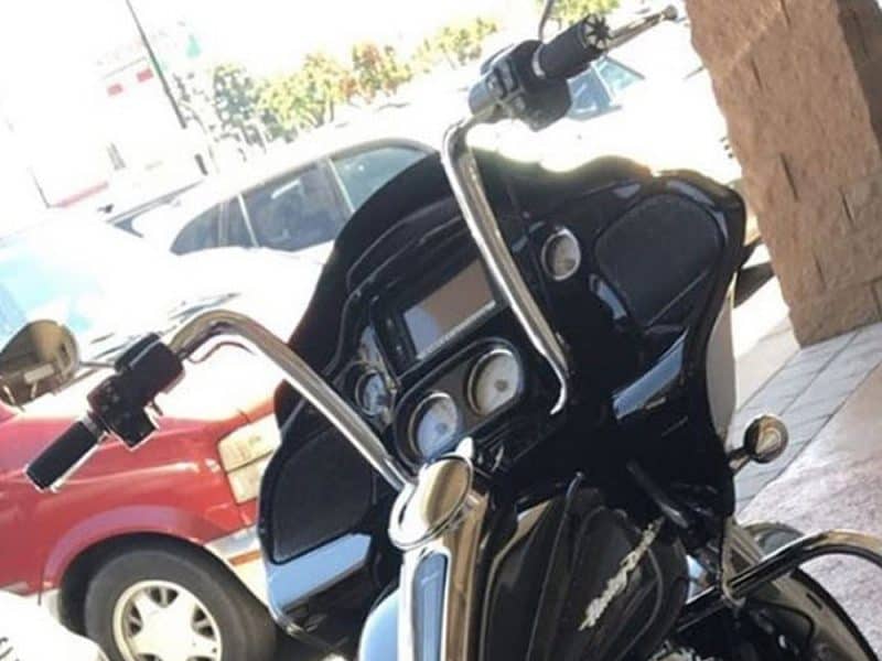 Vintage black motorcycle dashboard with chrome handlebars and digital display, parked outside Revelry Cycles.