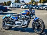 Blue and orange custom motorcycle with Harley Davidson design in a parking lot.