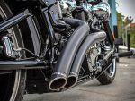 Exhaust pipes on a black motorcycle, showcasing custom chrome and matte finish.