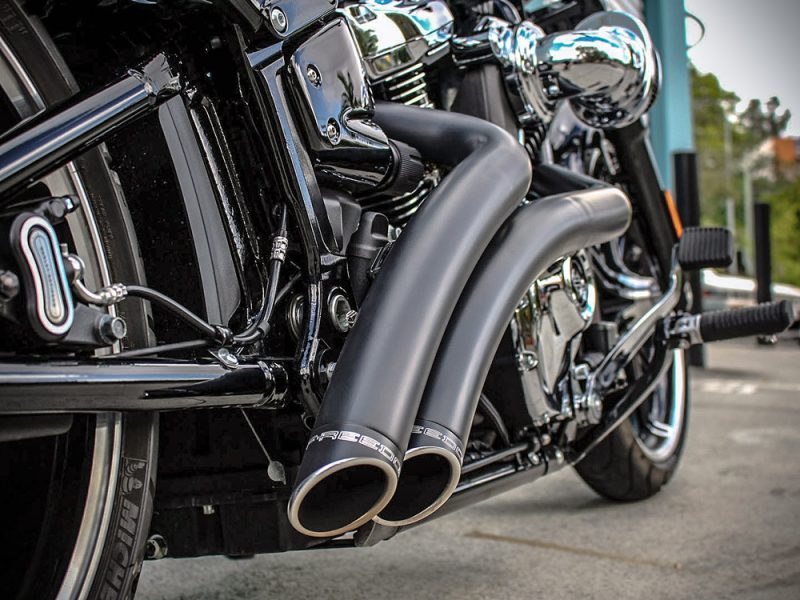Exhaust pipes on a black motorcycle, showcasing custom chrome and matte finish.