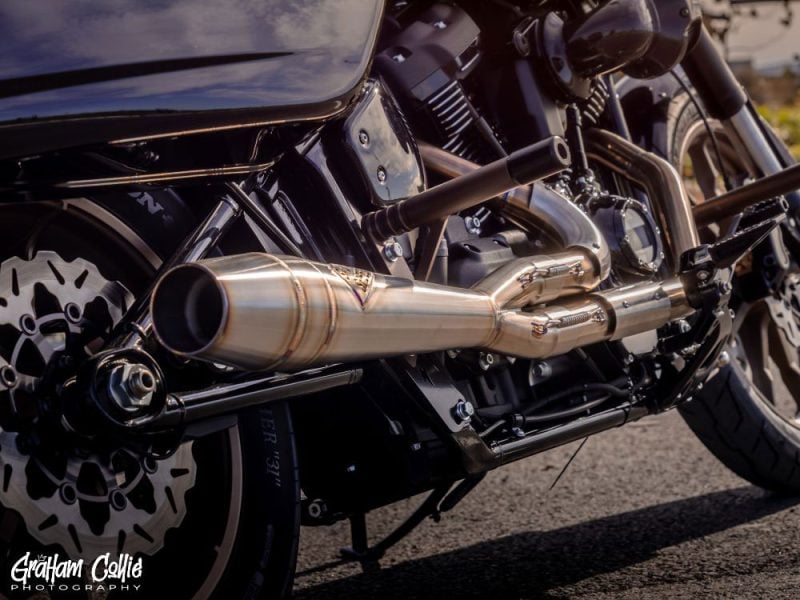 Menacing black motorcycle with chrome exhaust pipes and detailed engine components.