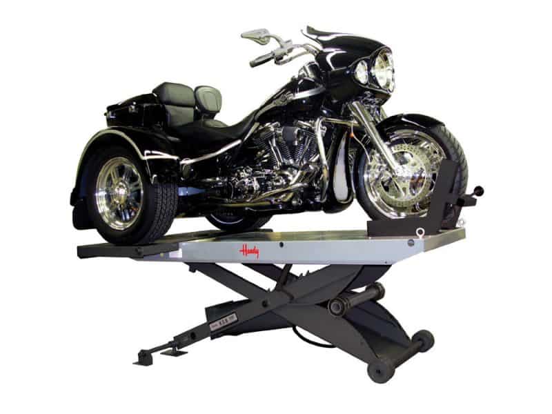 A black Harley-Davidson trike motorcycle on a hydraulic lift for maintenance or display.