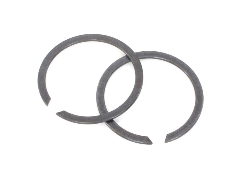 Two metal circlips for motorcycle engine repair or maintenance.