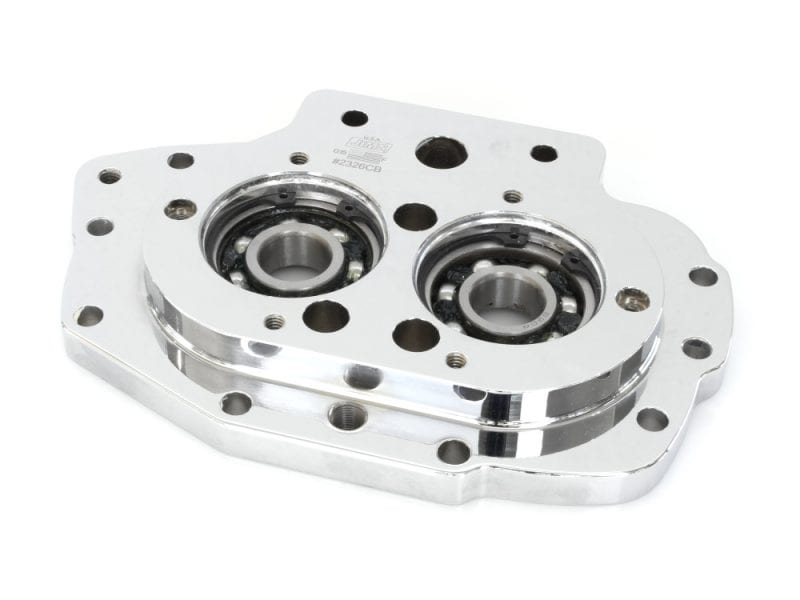 Transmission Trap Door with Exhaust Mounting Hole. Fits 5Spd Big Twin 1999-2006 Aluminium motorcycle engine component with dual ball bearings, chrome finish, flat mounting surface.