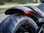 Black motorcycle tire with fender and red stitching details.