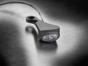 Modern motorcycle LED taillight positioned on a brushed metal surface.