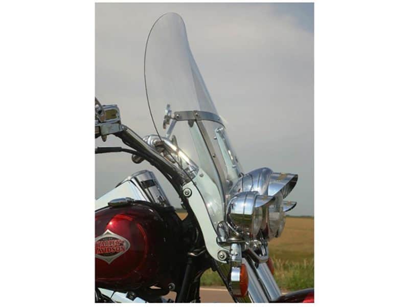 Shiny Harley Davidson motorcycle front view with windscreen and chrome details in an open field.