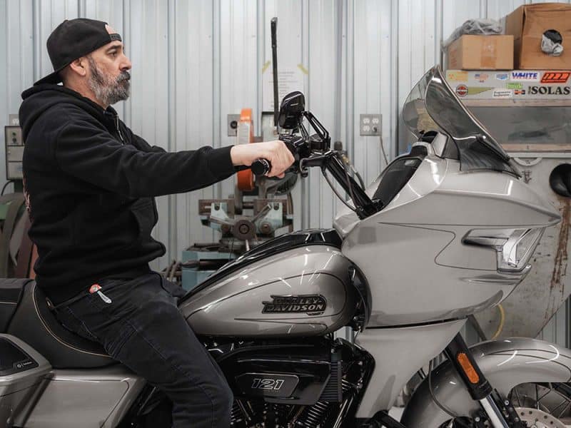 Harley Davidson motorcycle being serviced in workshop with mechanic.