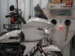 Harley Davidson touring motorcycle in a repair shop with workshop equipment in the background.