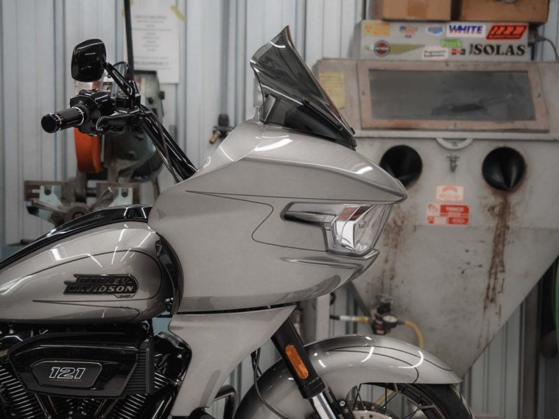 Harley Davidson touring motorcycle in a repair shop with workshop equipment in the background.