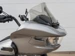 Sleek silver touring motorcycle with advanced windscreen and modern lighting for optimal touring comfort.