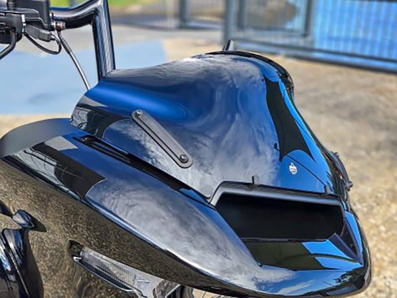 Shiny black motorcycle front fairing with blue accents and reflective surface.