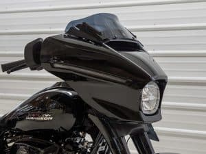 Bold black Harley-Davidson motorcycle with a sleek front headlamp and prominent windscreen.