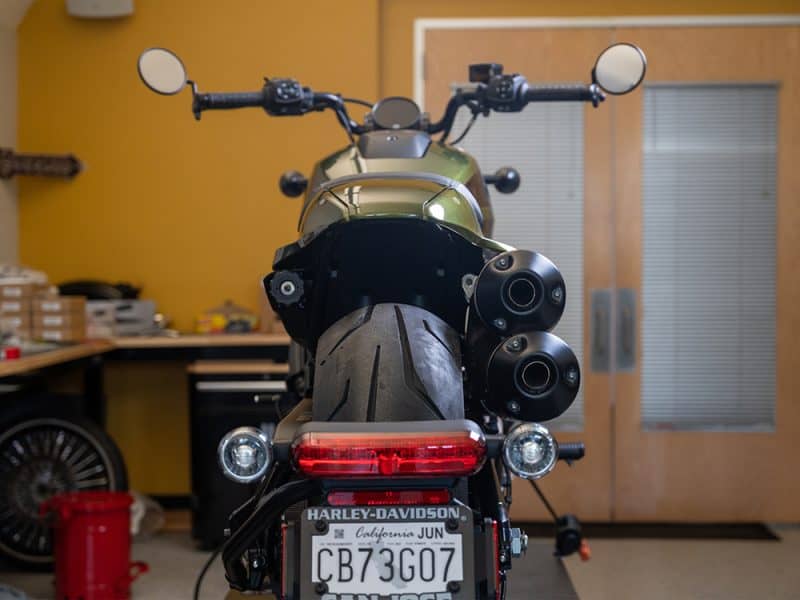 Harley-Davidson motorcycle rear view with dual exhaust pipes in a workshop setting.