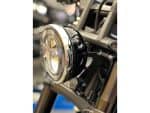 Chrome motorcycle headlight with black casing on a bike, showcasing stylish design.