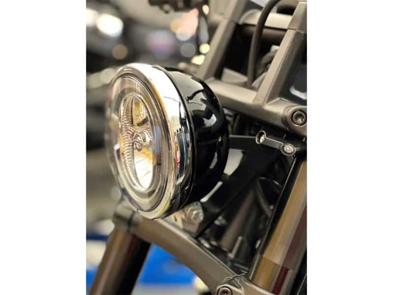 Chrome motorcycle headlight with black casing on a bike, showcasing stylish design.