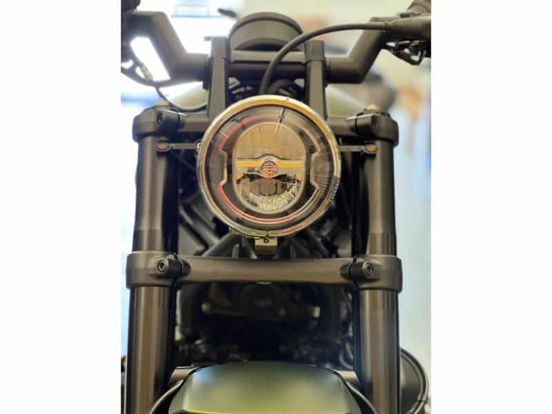 Riveting motorcycle headlight on a Revelry Cycles custom motorcycle in black finish.