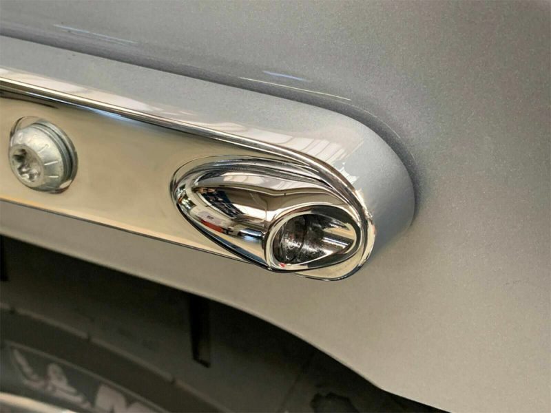 Shiny chrome motorcycle headlight and turn signal on a sleek vehicle, showcasing classic motorcycle design.