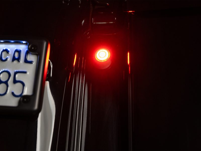 Revelry Motorcycles, red LED light on motorcycle, close-up of innovative motorcycle lighting, showcasing sleek design and safety features.