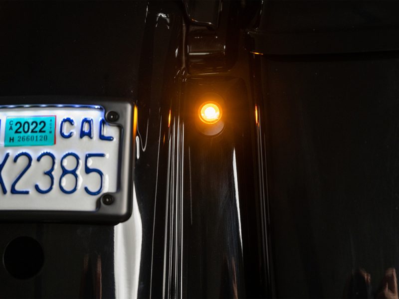 Vintage motorcycle rear LED indicator light and license plate, showcasing classic motorbike style.